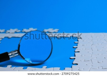 Problem solving concept. Magnifying glass over an incomplete jigsaw puzzle with copy space showing problem solving, analysis, strategy, clarity, and finding solutions.