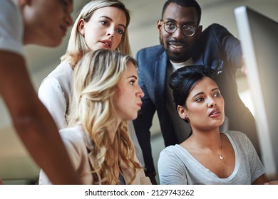 Problem solving done as a unit. Shot of a group of colleagues using a computer together in a modern office.