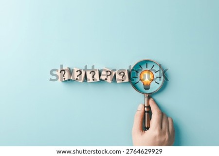 Problem Solving and Idea Discovery Concept. Hand holding magnifying glass over question mark blocks and light bulb representing creative thinking, solution search, innovation, answer finding, insight