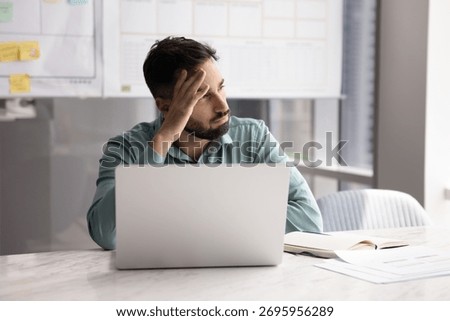Problem solving. Serious pensive young businessman sit at desk in modern planning office look aside from notebook screen contemplate complex project solution reflect on difficult task brainstorm ideas