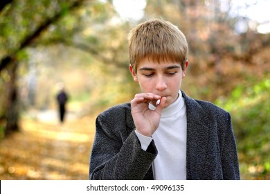 Problem Teenager Smoking Cigarette In The Park