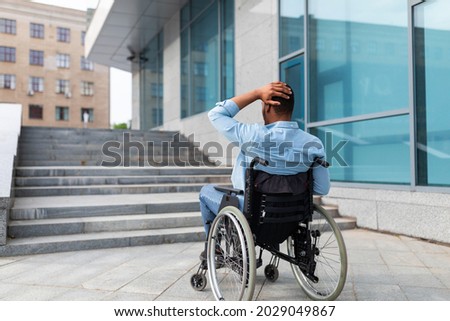Problems with accessible environment for disabled people. Irritated impaired black man in wheelchair having no possibility to enter building without ramp, outdoors. Empty space Photo stock © 
