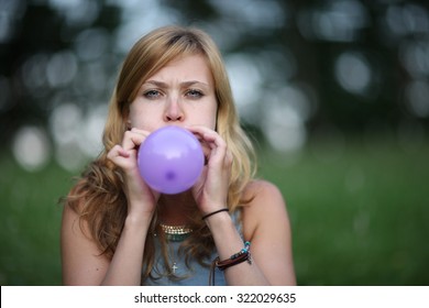 Problems blowing balloons; face of a woman inflating a balloon