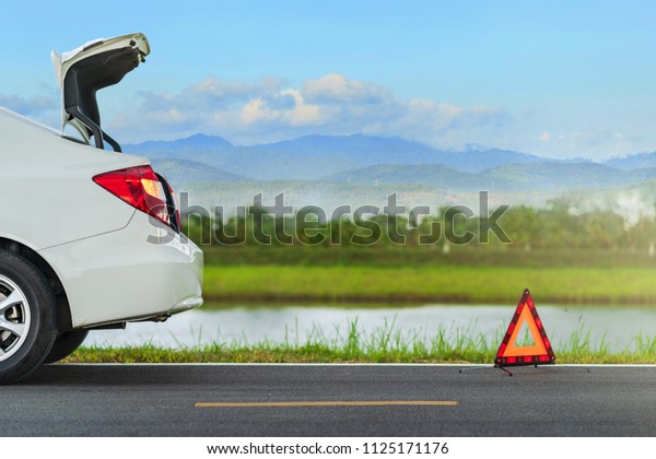 Problems\
car and a red triangle warning sign on the\
road