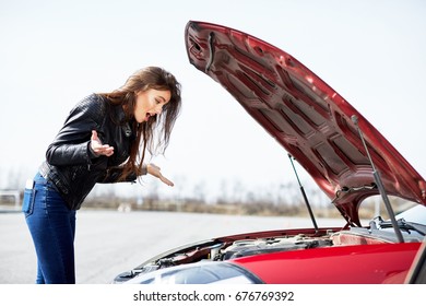 Problems With Engine, Confused Driver.  Profile Of Stressed  Woman Standing Near Car. Looking Inside Of The Red Broken Car, Outside