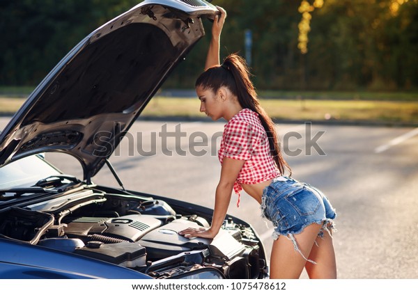 Problems\
with engine, confused driver. Stressed woman standing near car,\
broken down. Looking inside of the broken\
car.