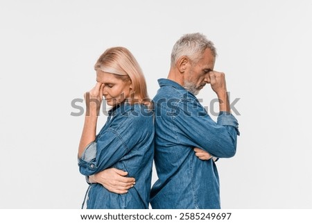 Problems in marriage, difficulties in relationships concept. Upset unhappy elderly married couple have quarrel, standing apart with arms crossed on chest, dont talk to each other, beige background