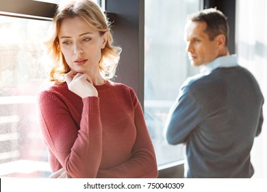 Problems In Relationships. Sad Unhappy Cheerless Woman Standing Near Her Boyfriend And Holding Her Chin While Feeling Depressed