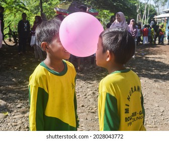 PROBOLINGGO, INDONESIA – 02 FEBRUARY, 2020 : In The Morning, Two Children Took Part In A Competition To Squeeze A Pink Balloon Between Two Heads To Prevent It From Falling To The Finish Line