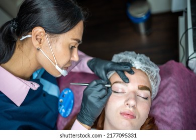 Procedure Of Eyebrow Microblading. A Master In Black Gloves Is Doing A Blending Needle Of Model's Brow. High Quality Photo