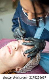 Procedure Of Eyebrow Microblading. A Master In Black Gloves Is Doing A Blending Needle Of Model's Brow. High Quality Photo