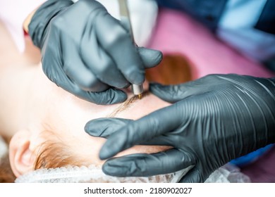 Procedure Of Eyebrow Microblading. A Master In Black Gloves Is Doing A Blending Needle Of Model's Brow. High Quality Photo