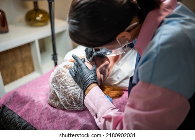 Procedure Of Eyebrow Microblading. A Master In Black Gloves Is Doing A Blending Needle Of Model's Brow. High Quality Photo