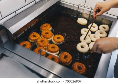 Procedure Of Making Donuts In A Small Town Donut Bakery - Putting Donuts In A Deep Fryer. Selective Focus.