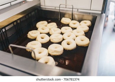 Procedure Of Making Donuts In A Small Town Donut Bakery -  Donuts Frying In A Deep Fryer. Selective Focus. 