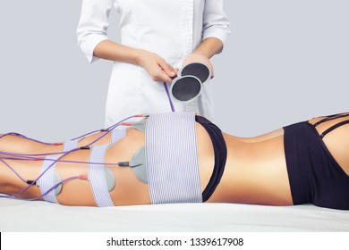 The procedure of myostimulation on the legs and buttocks of a woman in a beauty salon. Caring for the body, reducing excess weight.