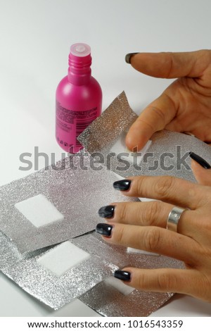 The procedure for removing varnish from nails (hybrid varnish) in progres. 
A woman's hand with foils. [[stock_photo]] © 