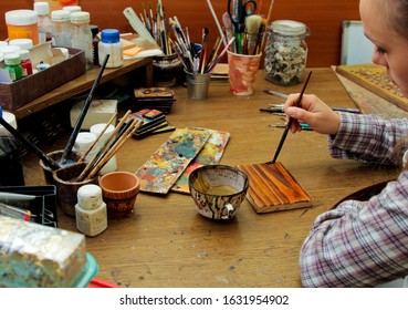 Process Of Aging Of A Wooden Picture, Processing Of Wood, Toning With Wood Stain. Girl Artist Paints A Picture In The Studio. Brushes And Paints On The Background.