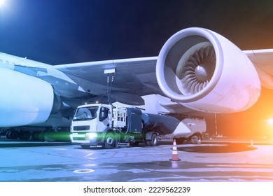 Process of aircraft refueling using a tanker truck connected to the fuel tanks of the aircraft with hoses at night airfield - Shutterstock ID 2229562239