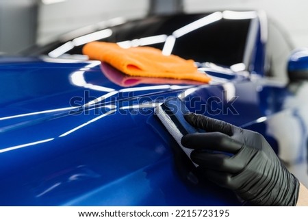 Process of applying ceramic protective coat on body car using sponge in detailing auto service. Car service worker apply ceramic coating to protect the car body from scratches