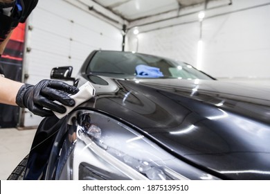 The process of applying a nano-ceramic coating on the car's hood by a male worker with a sponge and special chemical composition to protect the paint on the body from scratches, chips and damage.