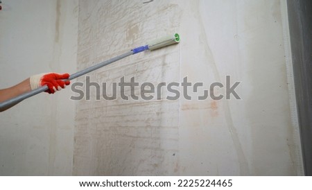 The process of applying a primer with a roller. The process of applying a primer to a wall using a roller. The primer solution is applied to the wall using a roller, so as to remove dust and increase 