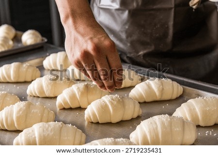 The process of baking bread: Baker's hand sprinkling sea salt on top of fresh salt bread dough (Shio Pan) before baking