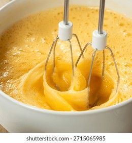 The process of beating eggs with sugar with a mixer, close-up, making the dough