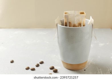 The process of brewing a bag Drip coffee into a cup on a gray background. A quick way to prepare a tasty and aromatic drink. Horizontal orientation. Selective focus. Copy space