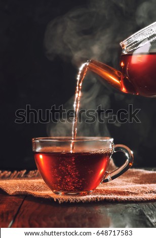 Process brewing tea,tea ceremony,Cup of freshly brewed black tea,warm soft light, darker background.