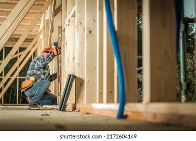 Process Of Building New Wooden Residential Houses. Checking The Level Of Building Carcass Walls With A Spirit Level Tool By Carpenter. Construction Industry Theme.