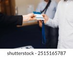 Process of checking in on conference congress forum event, registration desk table, visitors and attendees receiving lanyard with name badge and entry wristband bracelet and register electronic ticket