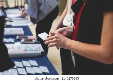 Process of checking in on a conference congress forum event, registration desk table, visitors and attendees receiving a name badge and entrance wristband bracelet and register electronic ticket
 - Shutterstock ID 2140275863
