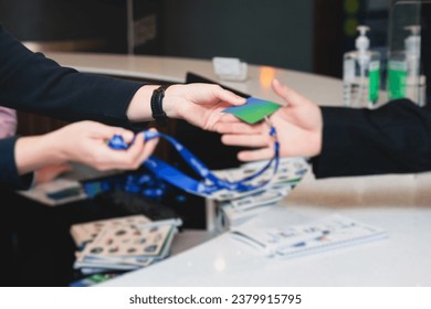 Process of checking in on a conference congress forum event, registration desk table, visitors and attendees receiving a name badge and entrance wristband bracelet and register electronic ticket
 - Powered by Shutterstock