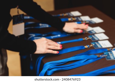 Process of checking in on a conference congress forum event, registration desk table, visitors and attendees receiving a name badge and entrance wristband bracelet and register electronic ticket
					