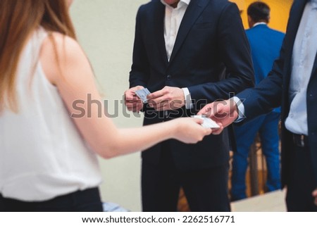Process of checking in on a conference congress forum event, registration desk table, visitors and attendees receiving a name badge and entrance wristband bracelet and register electronic ticket
