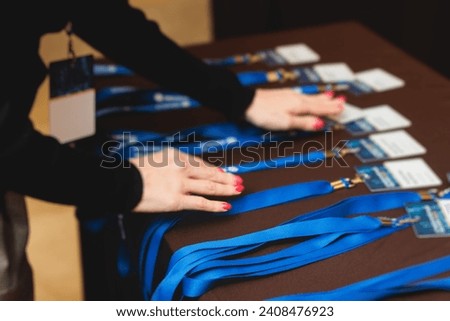 Process of checking in on a conference congress forum event, registration desk table, visitors and attendees receiving a name badge and entrance wristband bracelet and register electronic ticket
