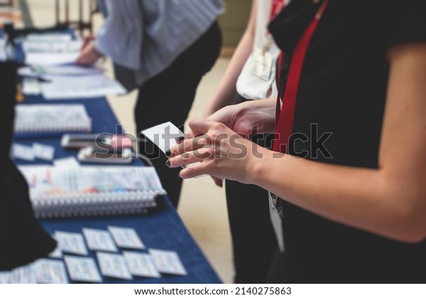 Process of checking in on a conference congress\
forum event, registration desk table, visitors and attendees\
receiving a name badge and entrance wristband bracelet and register\
electronic ticket\
