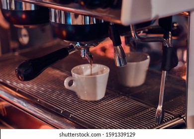 Process of coffee making, coffe machine is pourig fresh coffee to the white cup. - Shutterstock ID 1591339129
