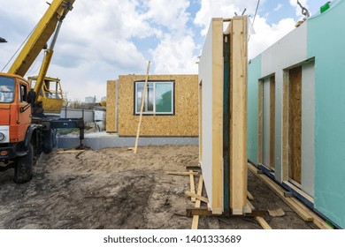 Process Of Construction New And Modern Modular House From Composite Sip Panels. Energy Efficient Panel Standing Near New Building And Crane