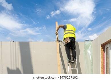 Process Of Construction New And Modern Modular House From Composite Sip Panels. Workman Standing On Ladder Near The Wall And Working On Building Development Industry Of Energy Efficient Property