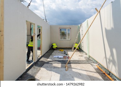 Process Of Construction New And Modern Modular House From Composite Sip Panels. Three Builder Man In Uniform Wear Working On Building Development Industry Of Energy Efficient Property