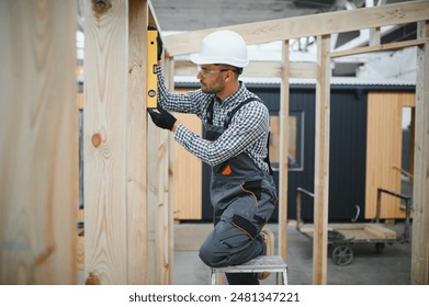 Process of construction new and modern modular house. Worker man in special protective uniform wear working on building development industry of energy efficient property.
