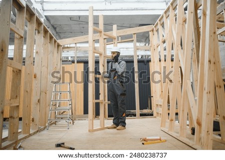 Process of construction new and modern modular house. Worker man in special protective uniform wear working on building development industry of energy efficient property.