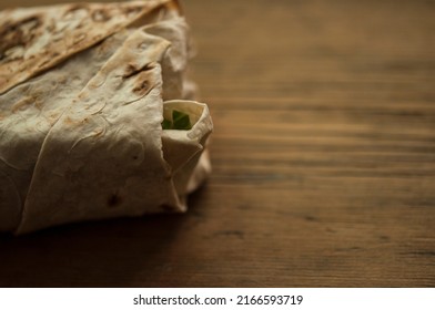 The process of cooking chicken wrap on kitchen table at home concept. Homemade kebab close up. Fresh thin lavash or pita bread roll of shawarma sandwich with ingridients inside.