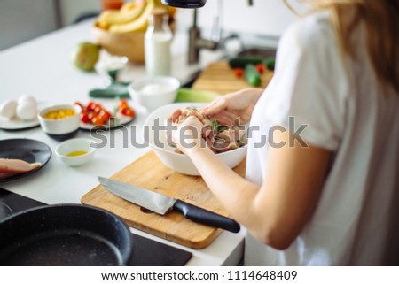 Process of cooking diet kebab. Cropped woman s hands marinating chiken meat with rosmarine spices and oil in dish on the table with kitchenware and food ingridients