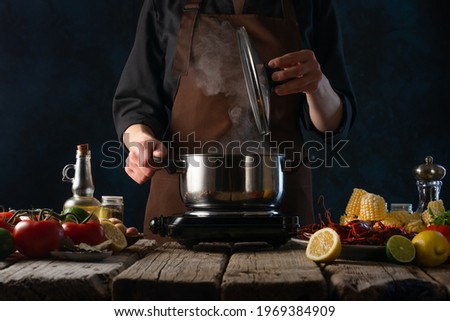 The process of cooking a dish of corn crayfish and potatoes. The chef cooks in a casserole on the background of ingredients. Cooking recipes.