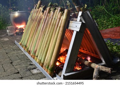 The process of cooking lemang using embers. Bamboo containing glutinous rice and coconut milk are arranged in parallel