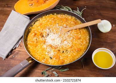 The process of cooking risotto with pumpkin - risotto in a pan with grated parmesan cheese on a table with ingredients, top view - Powered by Shutterstock