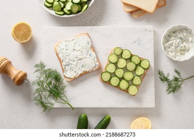 The Process Of Cooking Traditional English Tea Sandwiches With Cucumber And Cream Cheese For Breakfast On White Background. View From Above.